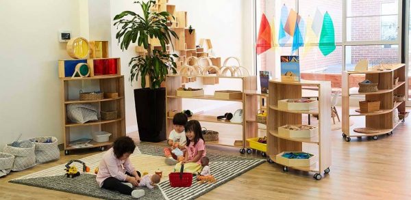 three children playing with dolls on floor at Guardian Marrickville