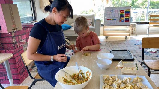 Educator making wontons with child at Caulfield
